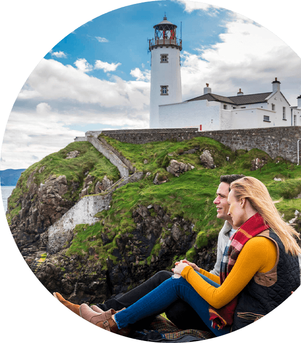 A couple sitting by the Fanad Head Lighthouse.